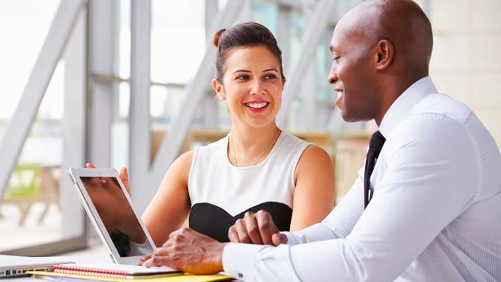 Woman and Man smiling sitting down using a laptop