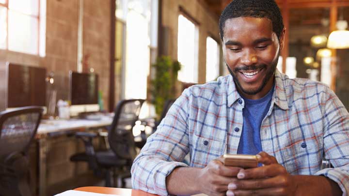 Hombre sonriendo mientras usa su teléfono